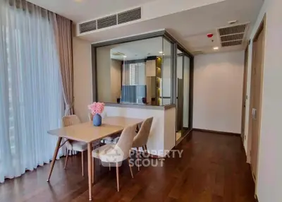 Modern dining area with elegant table and chairs, adjacent to a stylish enclosed kitchen.