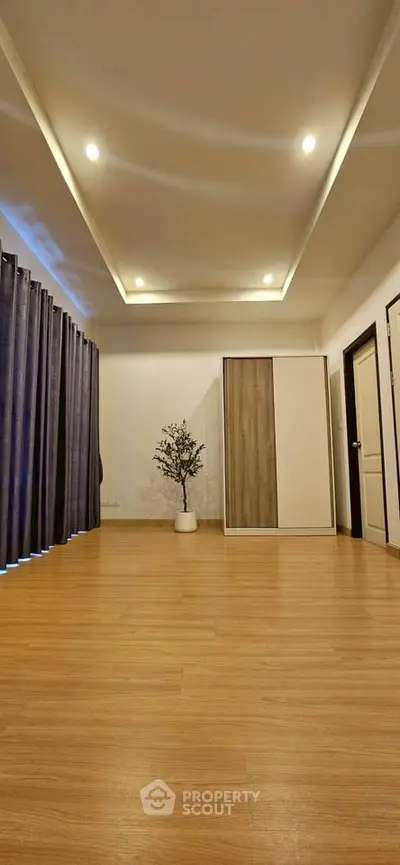 Spacious modern living room with wooden flooring and elegant ceiling lights.