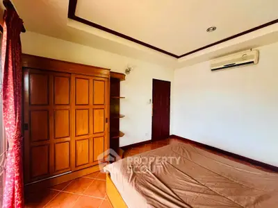 Spacious bedroom with wooden wardrobe and air conditioning in a cozy home.