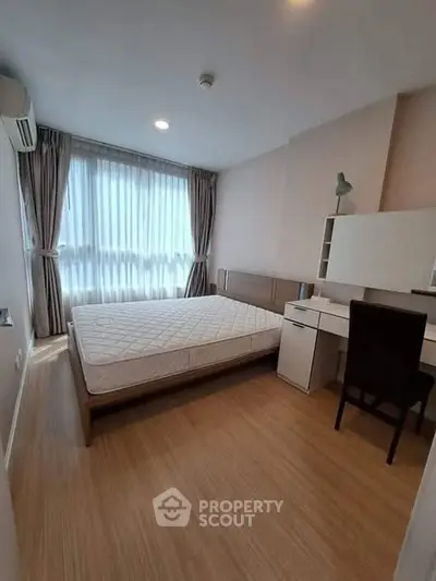 Spacious bedroom with natural light, featuring a comfortable bed and study desk, ideal for relaxation and productivity.