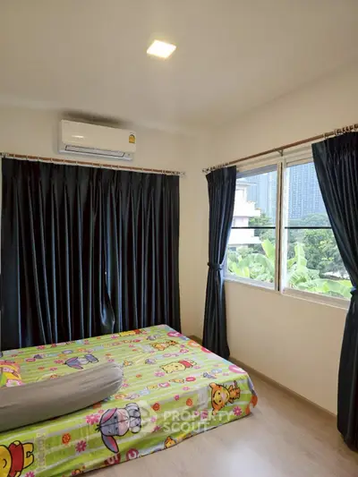 Cozy bedroom with vibrant bedding and city view, featuring air conditioning and large windows for natural light.