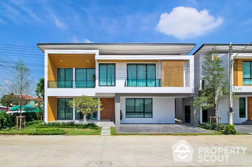 Modern two-story house with large windows and landscaped front yard