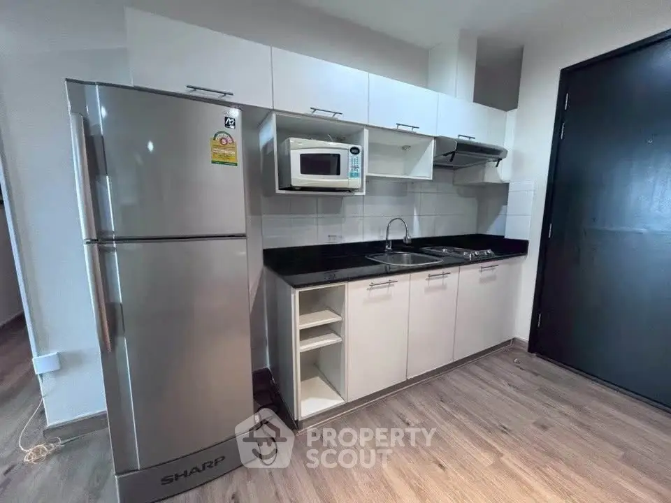 Modern kitchen with sleek appliances and stylish cabinetry in a contemporary apartment.