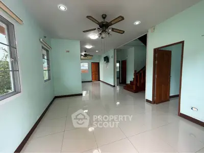 Spacious living room with ceiling fan and staircase in modern home