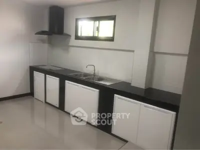 Modern kitchen with sleek black countertops and white cabinets, featuring a built-in sink and stove.