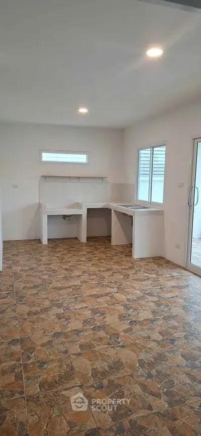 Spacious kitchen with tiled flooring and ample natural light, perfect for culinary creativity.