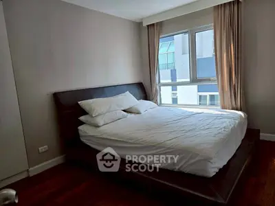 Cozy bedroom with modern bed and large window offering natural light