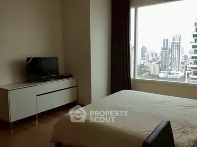 Modern bedroom with city view, featuring sleek furniture and large window.
