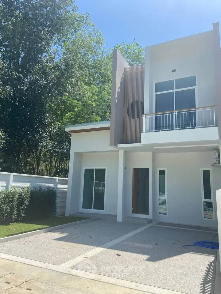 Modern two-story house with sleek design and spacious driveway, surrounded by lush greenery.