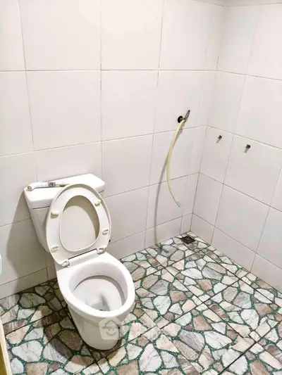 Simple bathroom with tiled floor and white toilet in a real estate property.