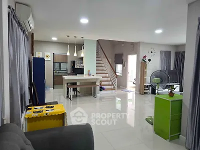 Spacious open-plan living room with modern kitchen and staircase, perfect for family gatherings.