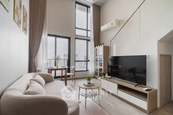 Modern living room with high ceilings and large windows offering city views.