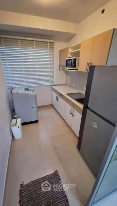 Compact kitchen with modern appliances and washing machine, ideal for efficient living.