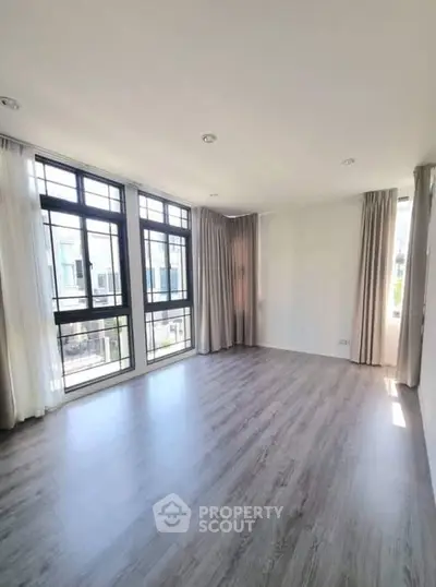 Spacious empty room with large windows and elegant curtains