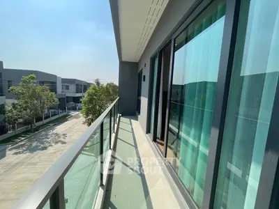 Spacious balcony with glass railing offering a serene view of modern residential area.