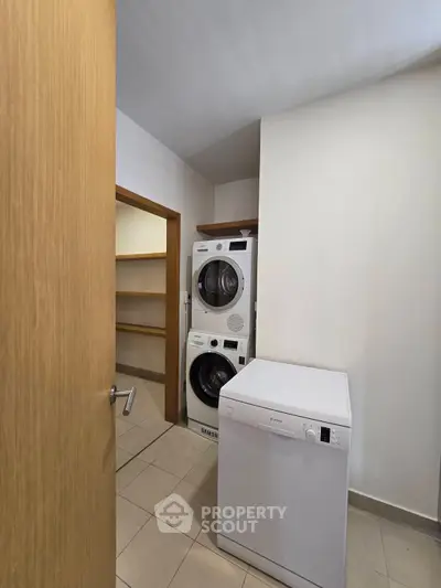 Modern laundry room with stacked washer and dryer, featuring ample shelving space.