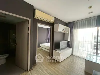 Modern living room with TV, air conditioning, and balcony access in a stylish apartment.