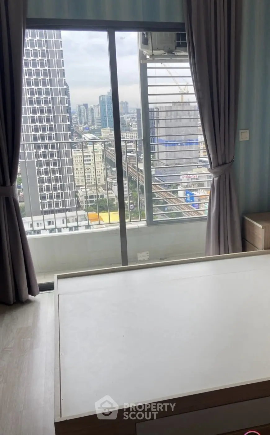 Modern bedroom with city view and large windows in high-rise apartment