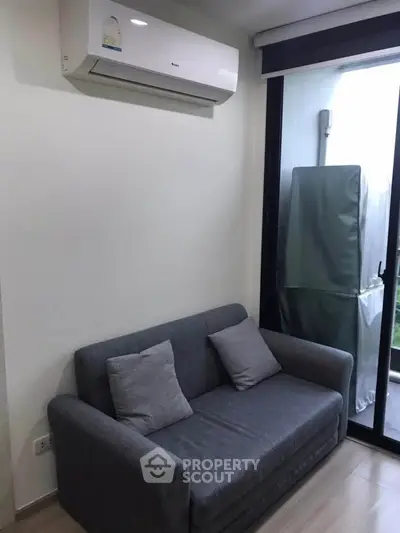 Cozy living room with modern air conditioning and compact sofa near a balcony.