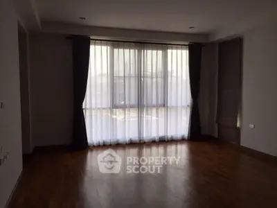 Spacious empty room with large windows and wooden flooring