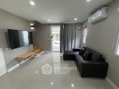 Modern living room with sleek furniture and wall-mounted TV, featuring a minimalist design.