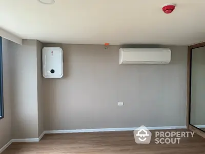 Modern room with air conditioning and water heater, featuring wooden flooring and neutral walls.