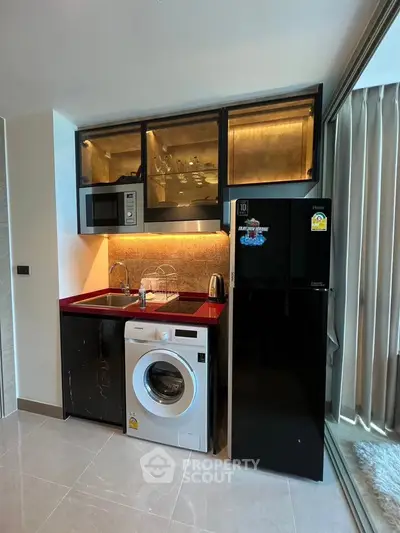 Modern compact kitchen with washing machine and fridge in stylish apartment