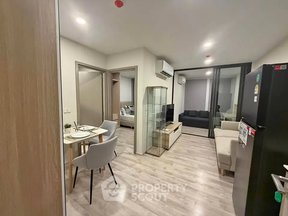 Modern apartment interior with open living and dining area, featuring sleek furniture and bright lighting.