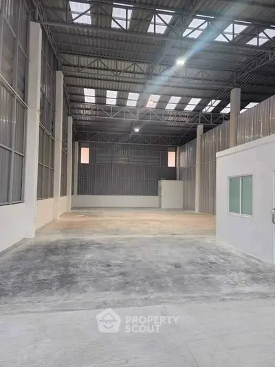 Spacious industrial warehouse with high ceilings and ample natural light.