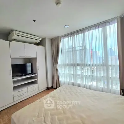 Bright bedroom with large window and modern furnishings in urban apartment.