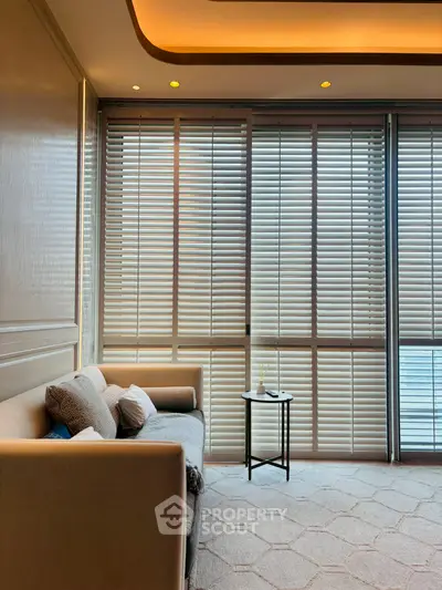 Luxurious living room with elegant sofa and floor-to-ceiling windows with blinds, offering a serene ambiance.