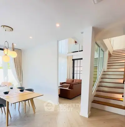 Modern open-plan living and dining area with stylish staircase and elegant lighting.