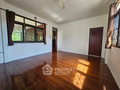 Spacious empty room with polished wooden floors and large windows