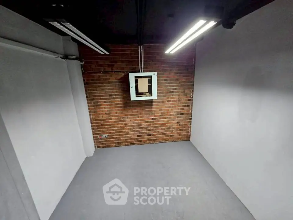 Industrial-style room with exposed brick wall and modern lighting, ideal for creative workspace or studio.
