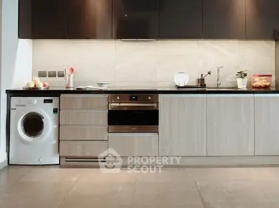 Modern kitchen with sleek cabinetry, built-in oven, and washing machine, perfect for contemporary living.
