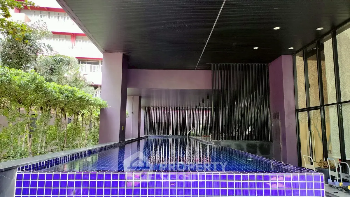 Luxurious indoor pool with modern design and vibrant purple tiles in upscale property.