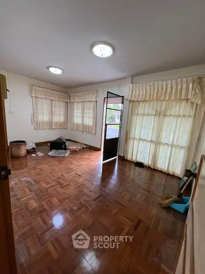 Spacious living room with wooden flooring and large windows for natural light.