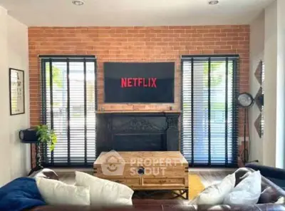 Stylish living room with exposed brick wall and modern decor, featuring a mounted TV and cozy seating area.