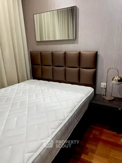 Cozy bedroom with modern decor and plush headboard, perfect for relaxation.