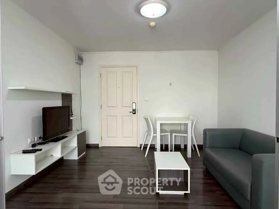 Modern living room with sleek furniture and minimalist design, featuring a cozy sofa and entertainment unit.