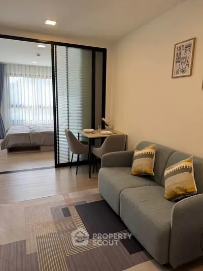 Modern living room with cozy sofa and view into stylish bedroom