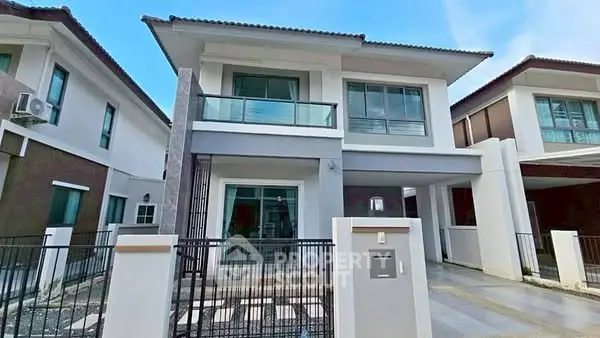 Modern two-story house with large windows and balcony in a suburban neighborhood.