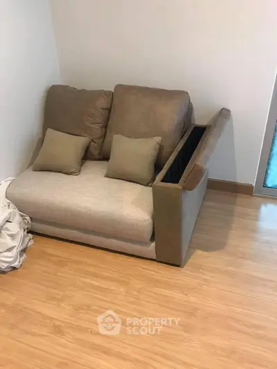 Cozy living room corner with modern sofa and wooden flooring, perfect for relaxation.