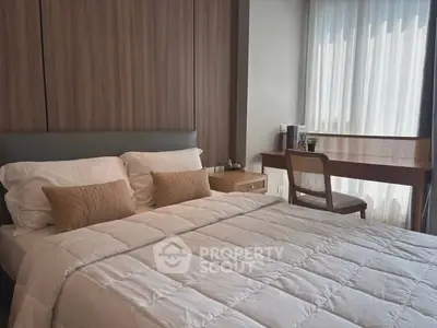Modern bedroom with cozy bedding and stylish wooden furniture, featuring a work desk by the window.