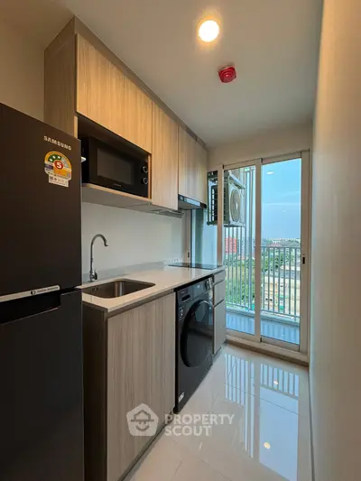 Modern kitchen with sleek appliances and balcony view in a stylish apartment.