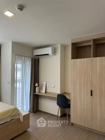 Modern bedroom with built-in wardrobe and study area, featuring sleek wooden finishes and natural light.