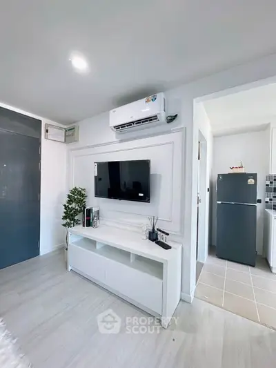 Modern living room with sleek TV setup and air conditioning, adjacent to a compact kitchen.