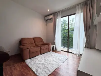 Cozy living room with leather sofa, wooden flooring, and balcony view in modern apartment.