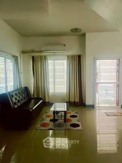 Spacious living room with modern sofa and stylish rug, featuring large windows for natural light.