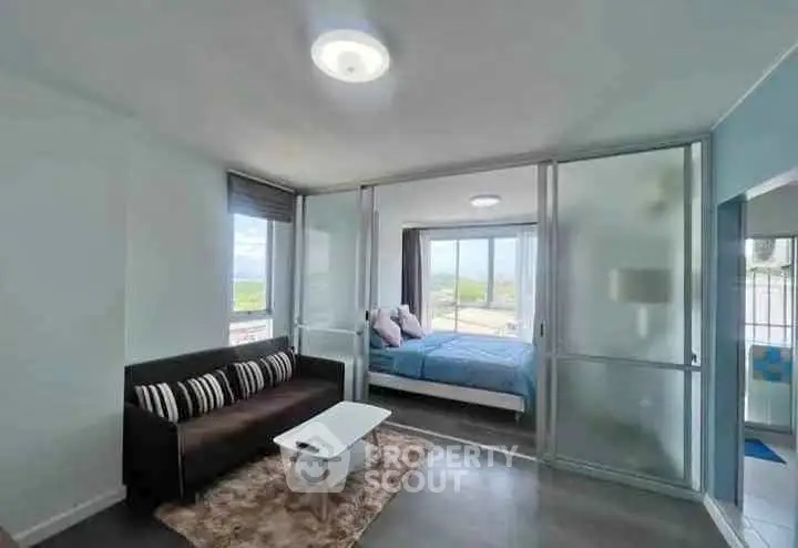 Modern apartment with glass partition, cozy living room, and bright bedroom with scenic view.